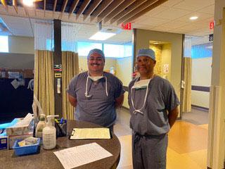 2 medical professionals in scrubs standing in a hospital lobby