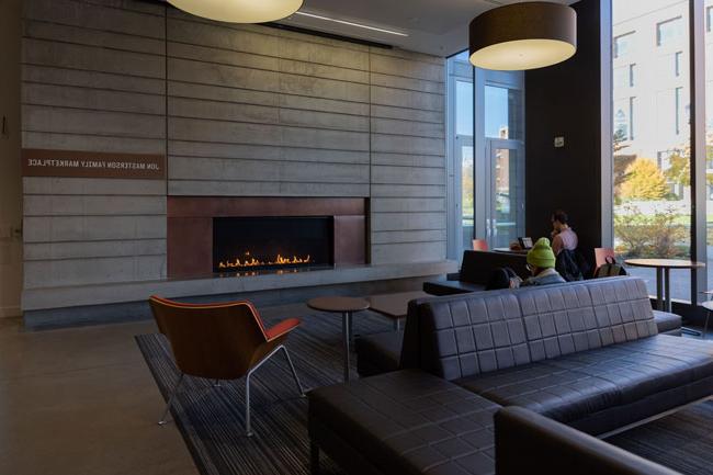 couch and tables in front of lit fireplace surrounded by stone slab