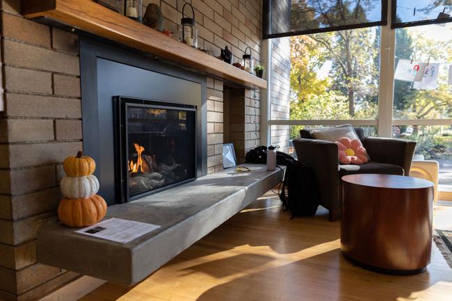 lit fireplace with a cushioned armchair and fall decorations