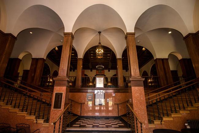 wooden staircase with overhead arches that splits left and right up the lobby of the Women's Building